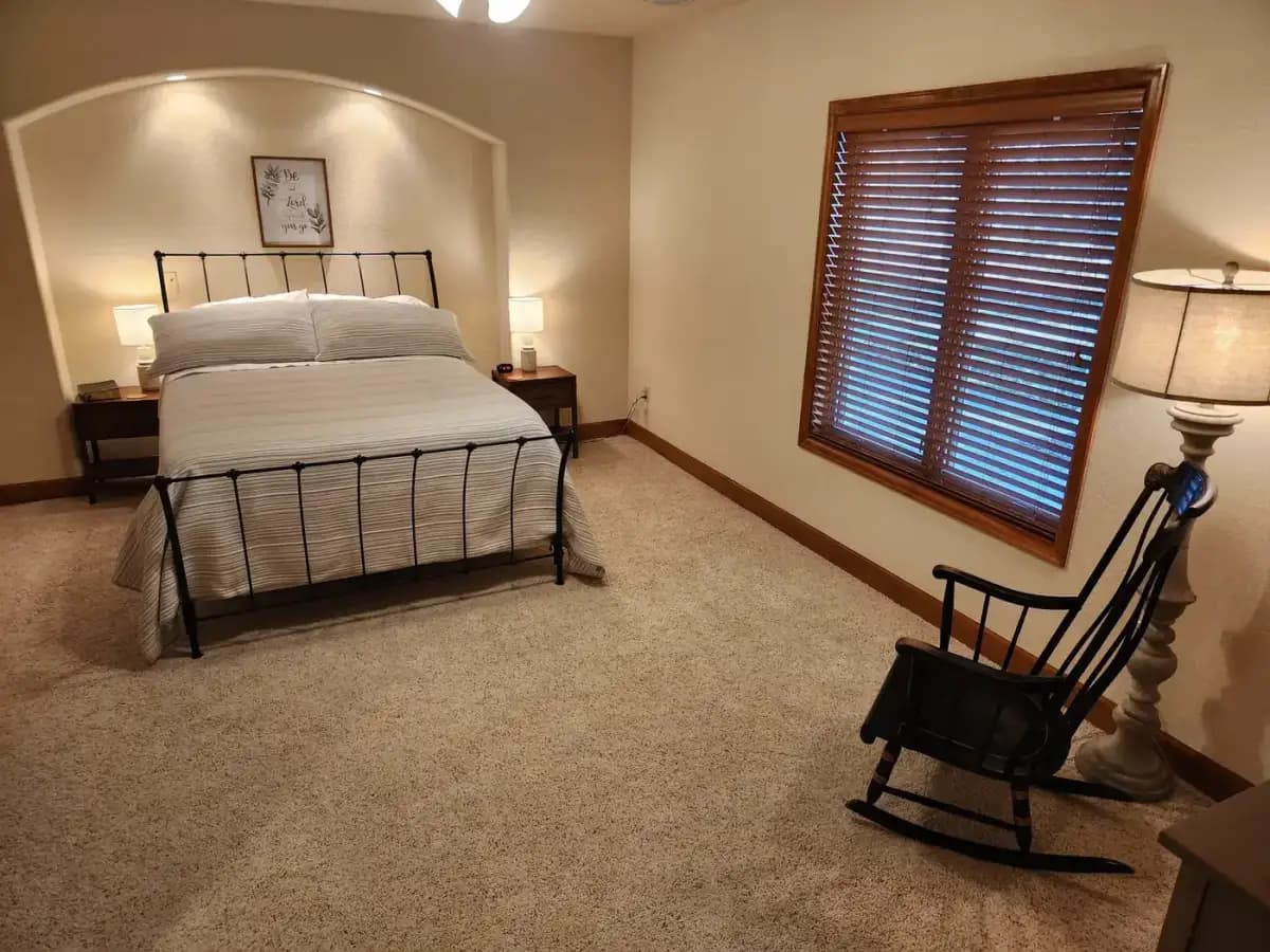 Denver Guest House bedroom with iron bed frame and rocking chair in guest accommodation